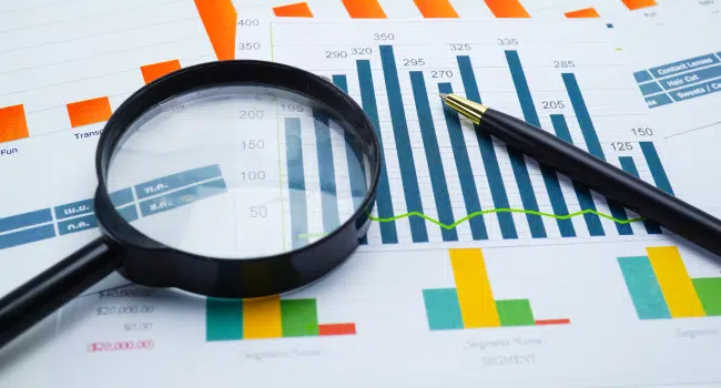 lupa e lápis sob um papel com gráficos e informações relacionadas a um site odontológico