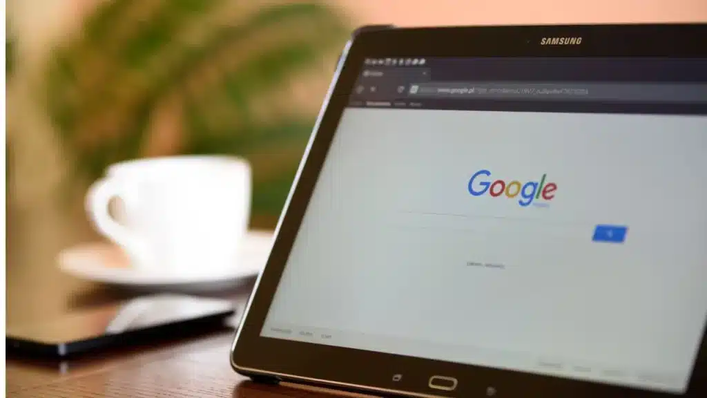 tela de um computador no site da google e ao fundo uma xícara de café