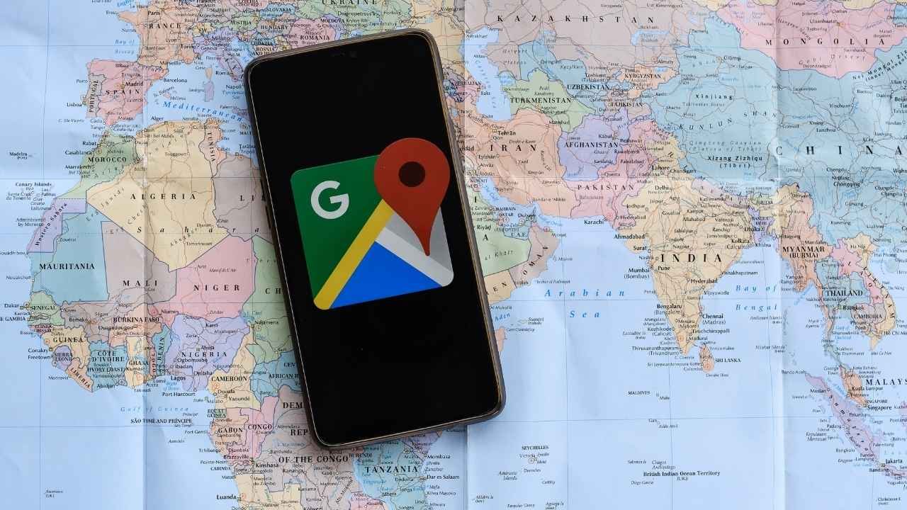 pin de localização e um celular encima de um mapa que representa o do google maps